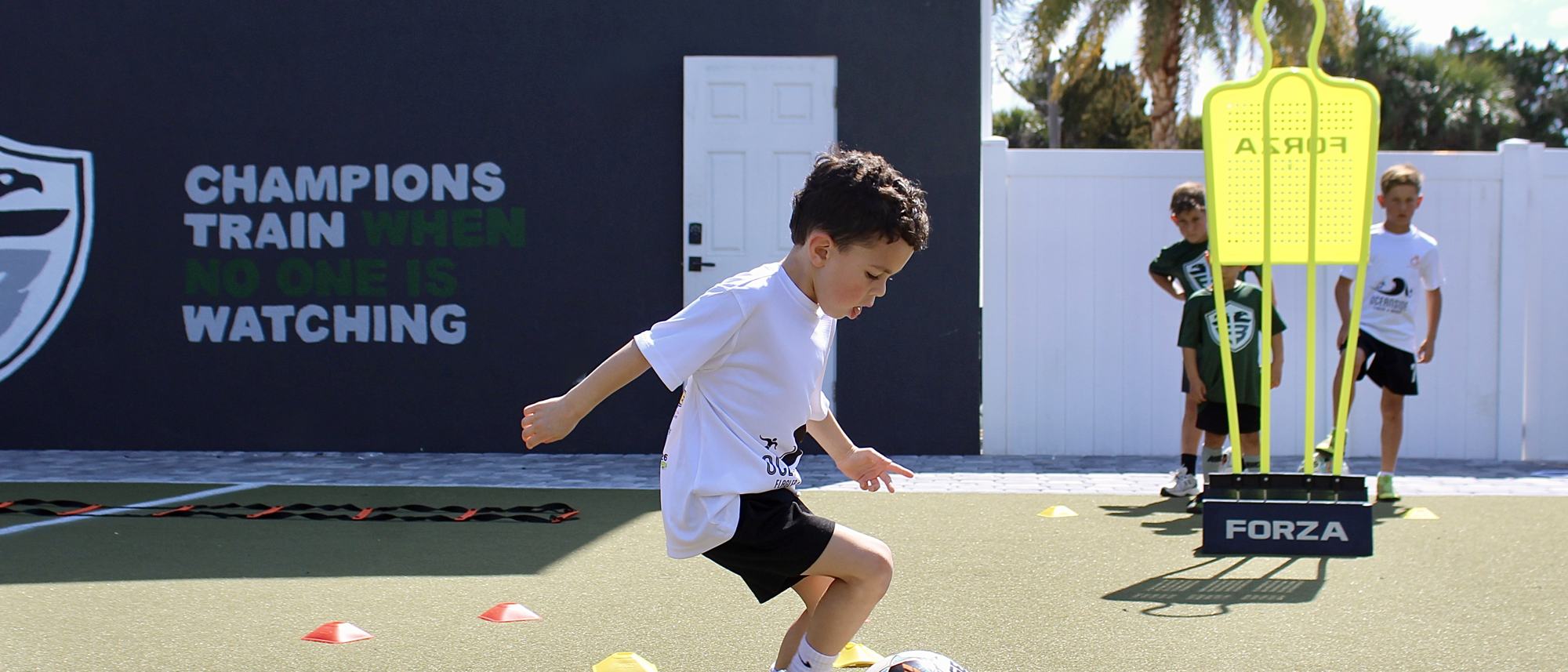 A student sprints past the academy's training wall, painted with the words Champions train when no one is watching.