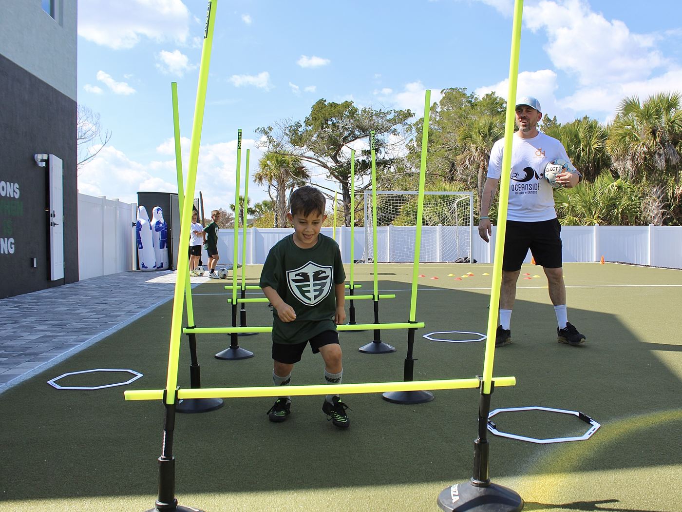 A student steps through a hurdle course while a coach watches.