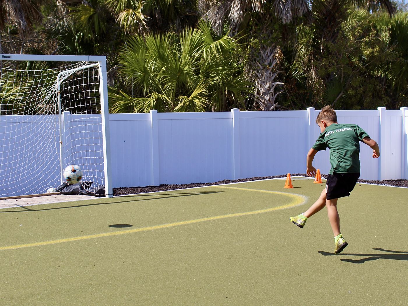 A student in a green jersey strikes the ball toward the goal.
